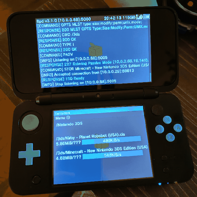 A photo of my 2DSXL sitting on my desk running FTPD, which turns the device into a file server. In this photo I am downloading Kirby: Planet Robobot and Minecraft