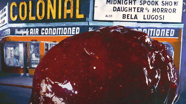 A red blob of goo rolls out of the front entrance of a movie theater.