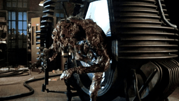 A lumpy, greasy bug creature emerges from a weird-looking machine