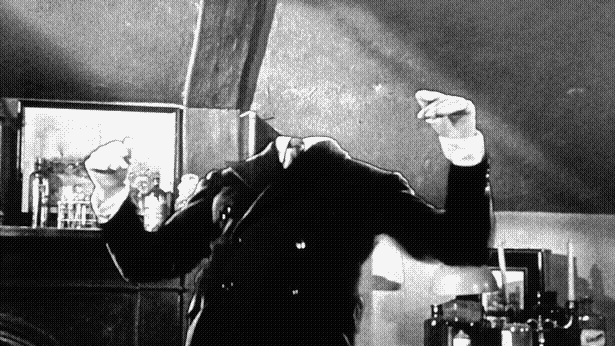 Black-and-white still of a guy in a suit posed as if he's laughing maniacally, but his head has been masked out of the shot